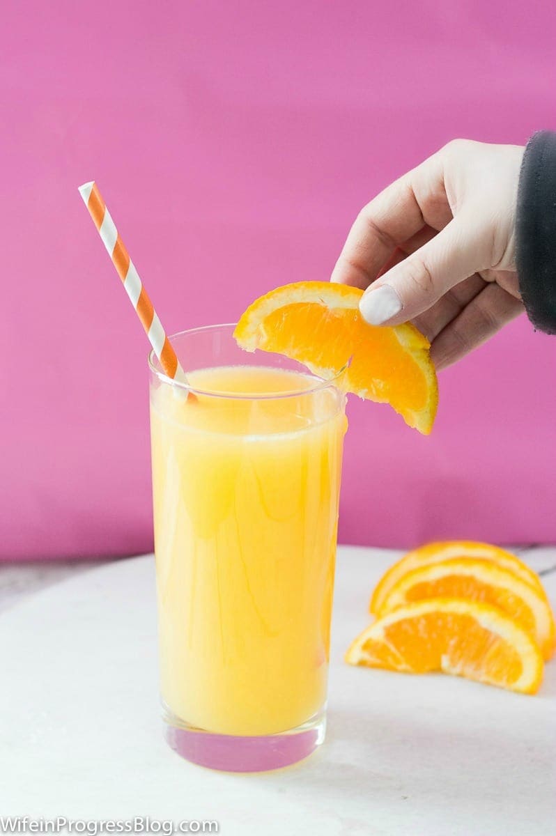 Placing an orange wedge on the rim of a glass, filled with juice