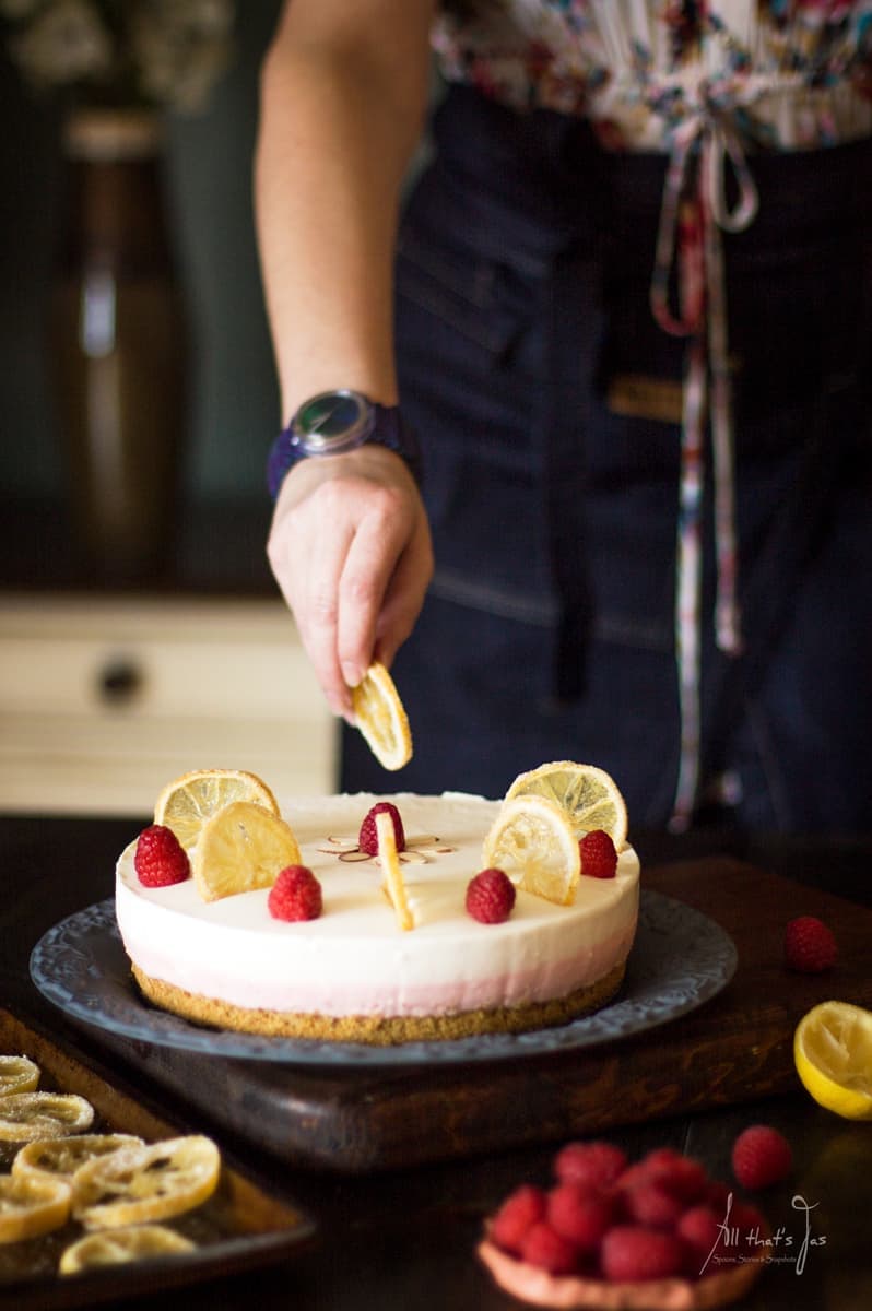Decorating the set cheesecake with lemons and raspberries