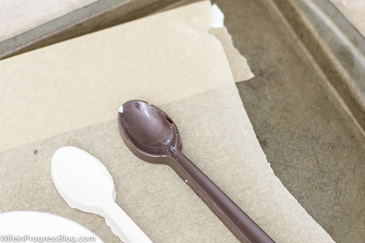 Chocolate spoons resting on parchment paper on a baking pan