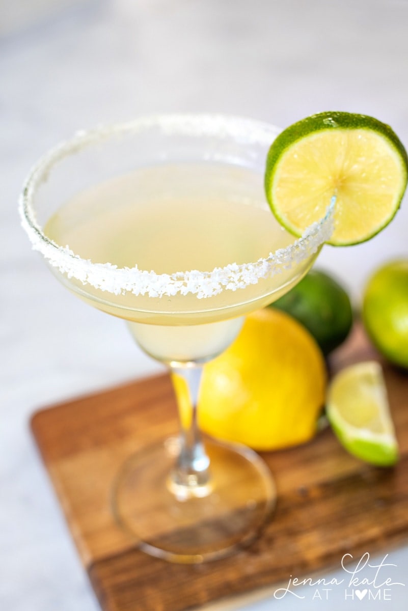 close up of a salt rimmed margarita glass garnished with a lime