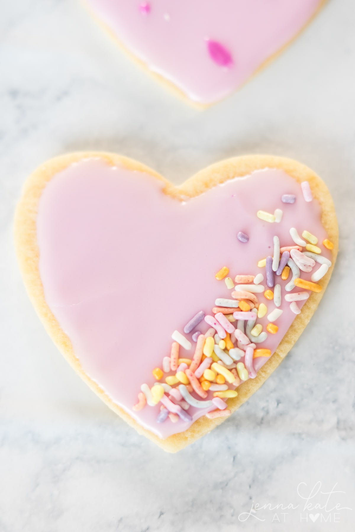 Close up of Valentine heart sugar cookie with pink frosting and sprinkles