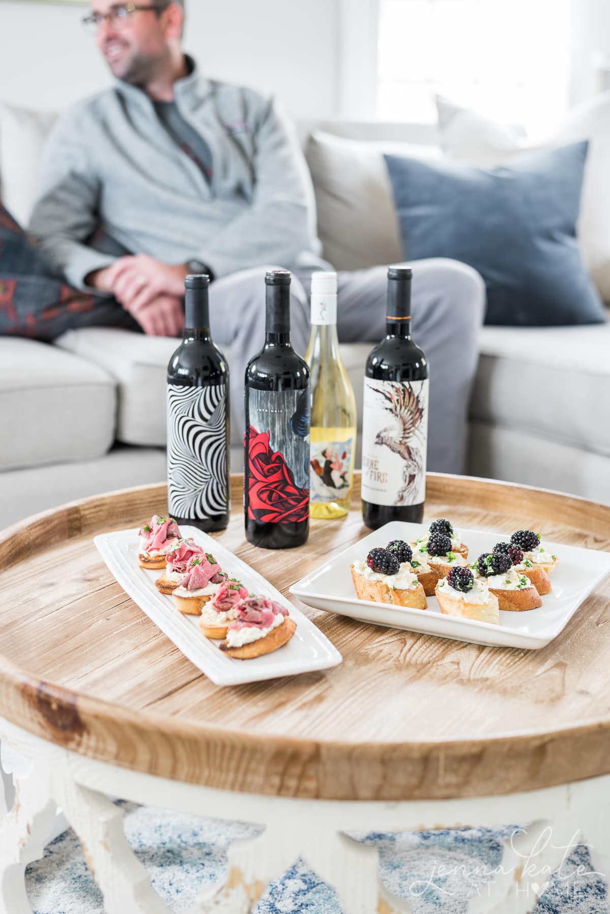 Various bottles of red and white wine on a coffee table with appetizers