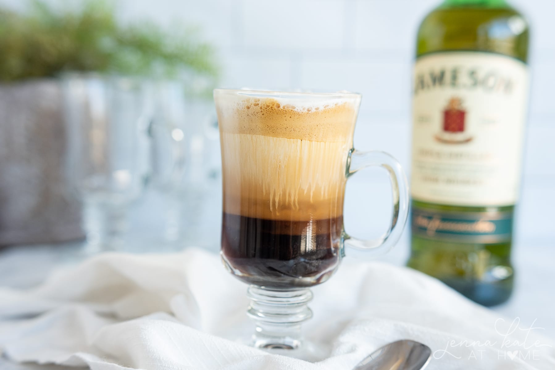 Glass of Irish coffee with a bottle of Jameson Irish whiskey in the background