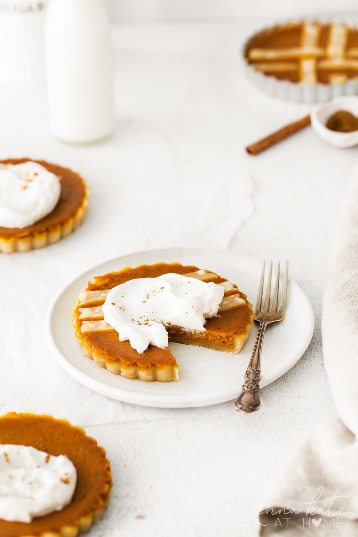 mini pumpkin pie on a plate with cream on top and a slice taken out