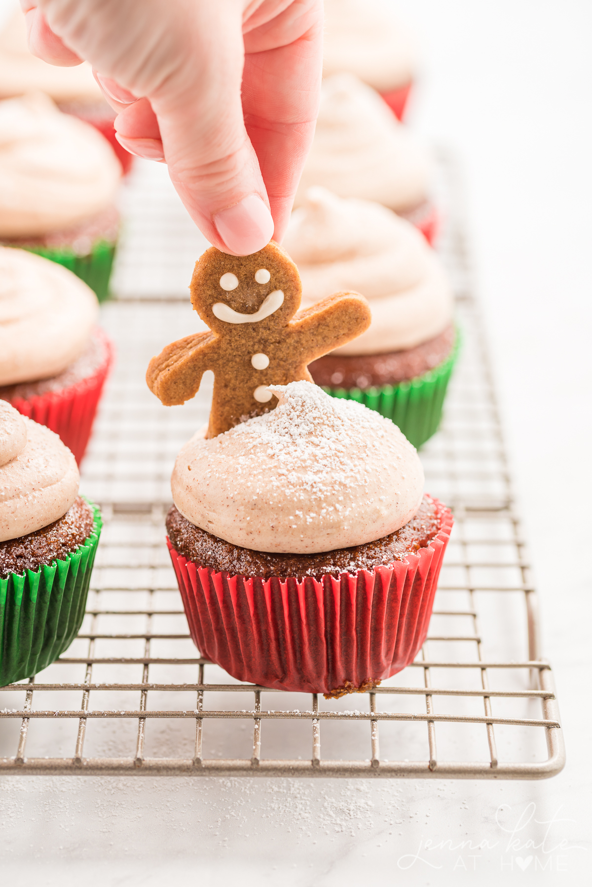 placing a gingerbread man into the top of one of the cupcakes