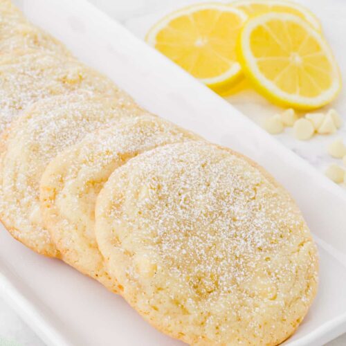 lemon drop cookies on a plate with lemons in the background