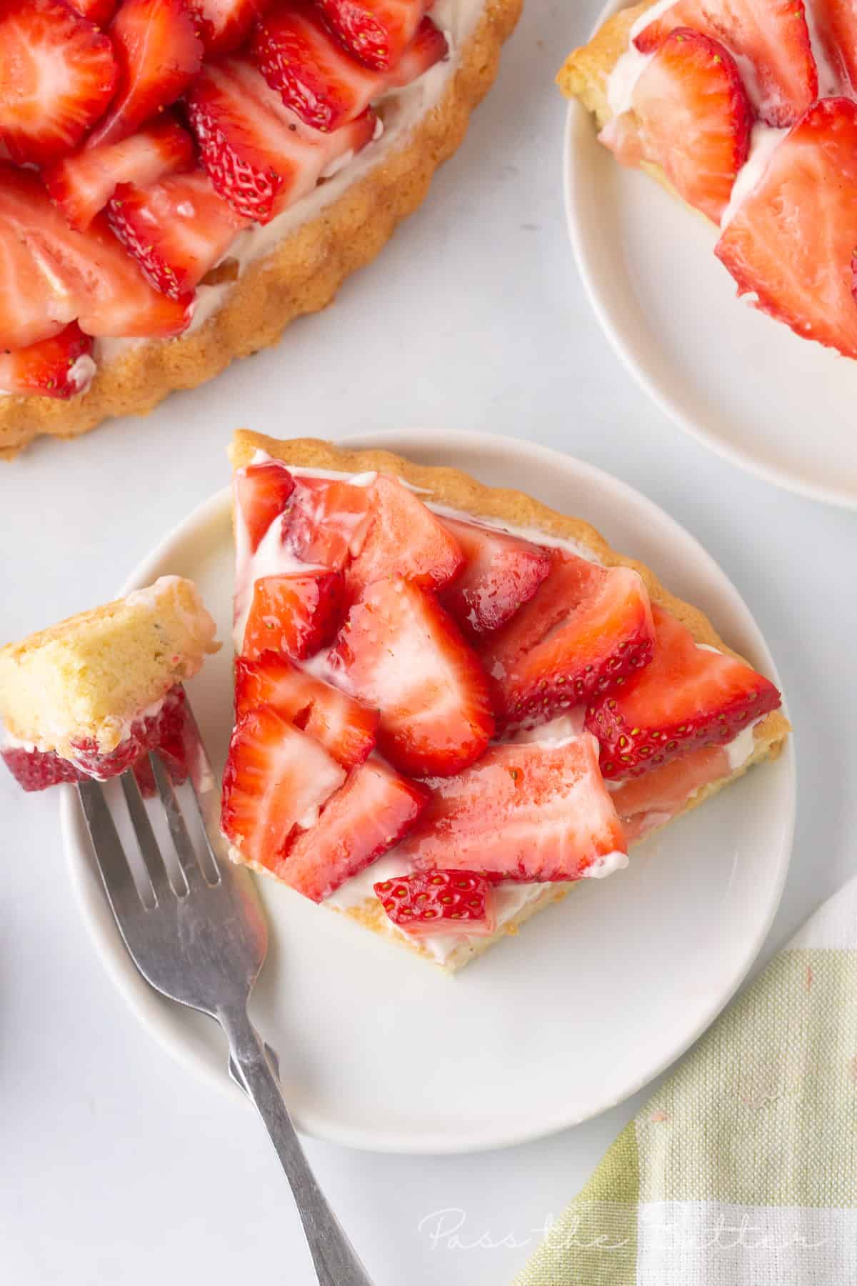 Piece of strawberry flan on a plate with a bite on a fork.  