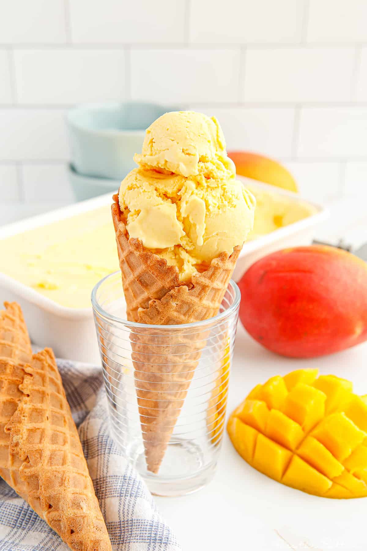 ice cream cone sitting in a glass and filled with a large scoop of mango ice cream