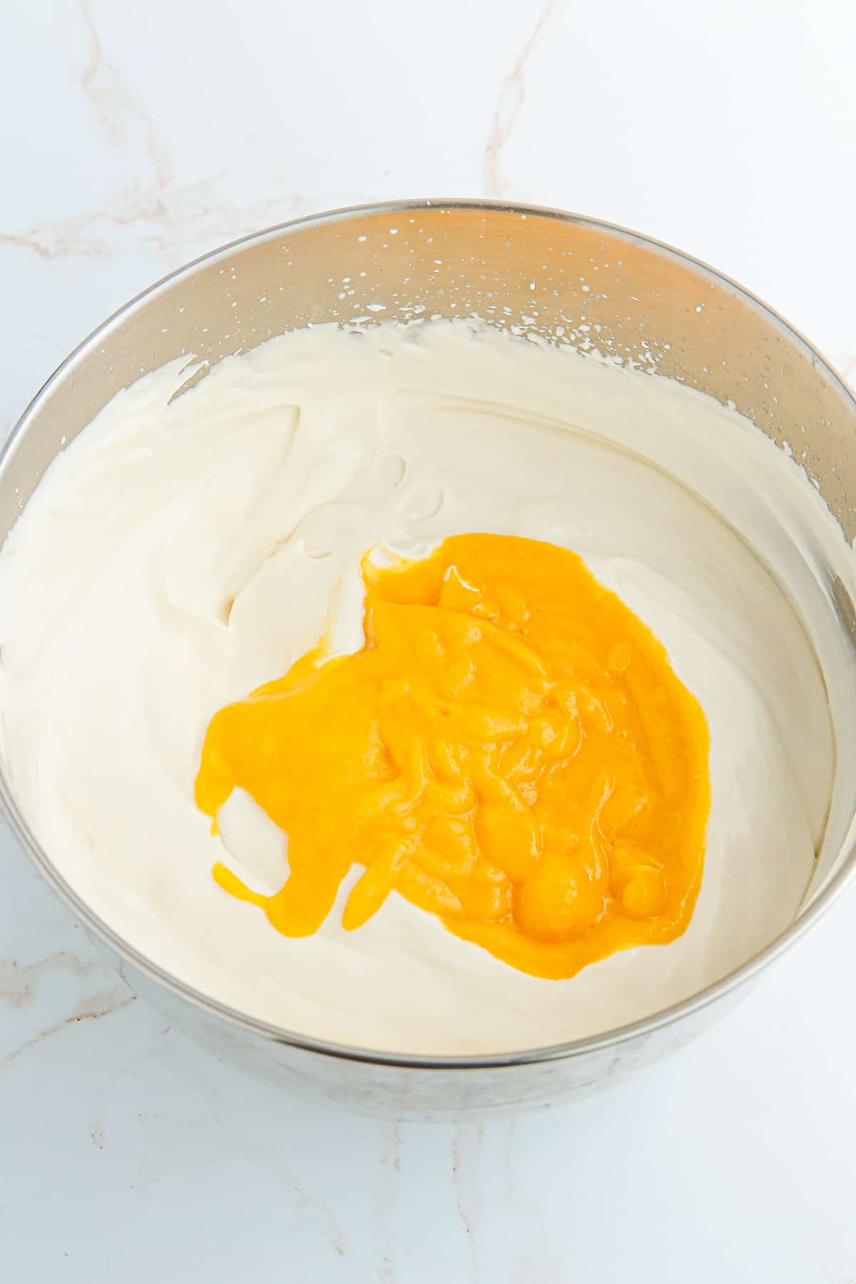 adding the mango puree to the whipped cream mixture