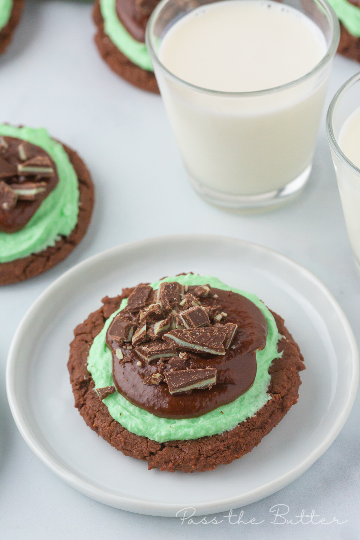 Grasshopper cookie on a plate wit a glass of milk behind it.